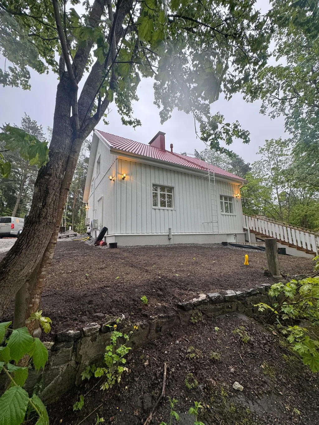 Vitt hus med rött tak och gård