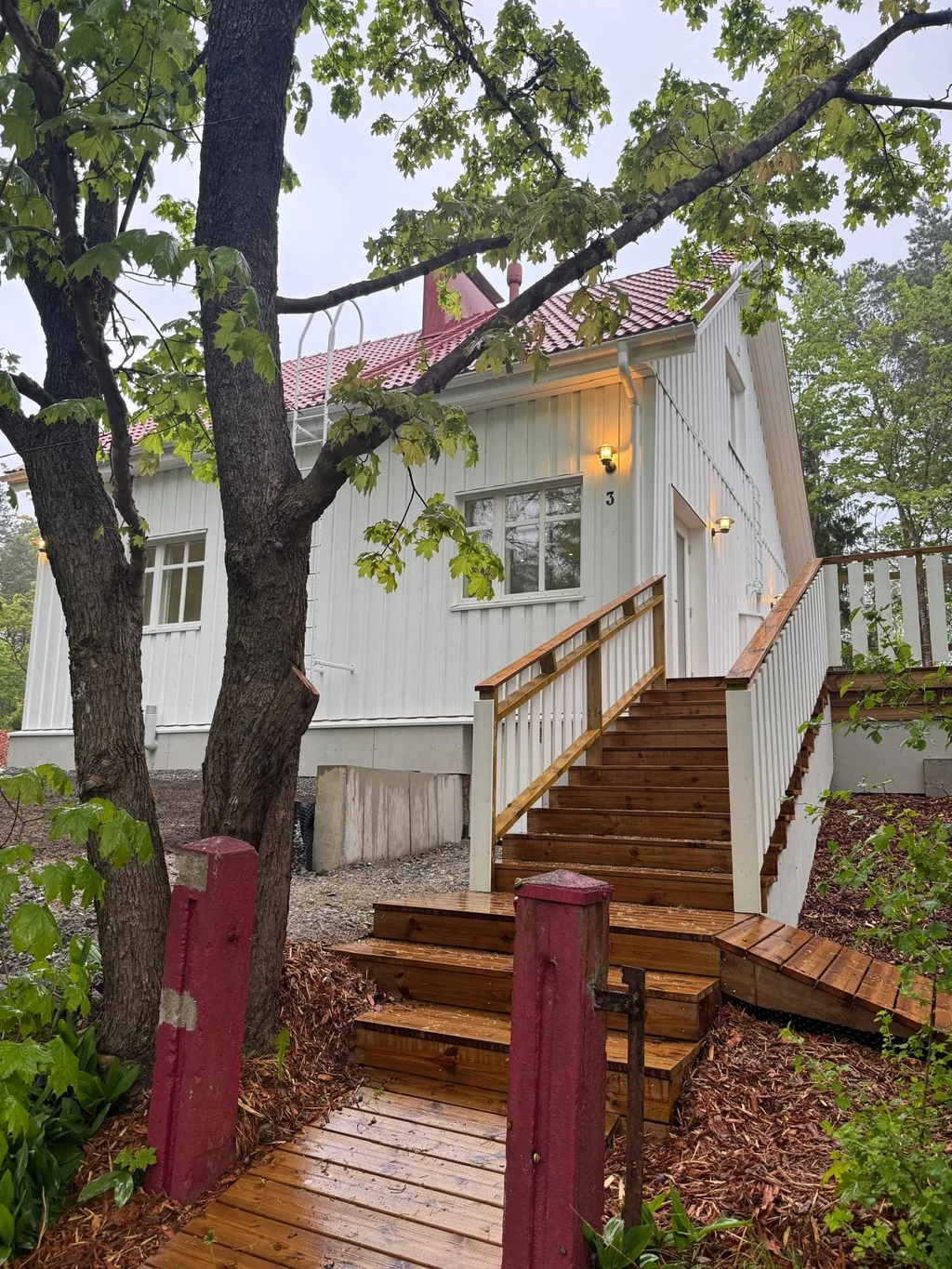 Vitt trähus med rött tak och terasstrappa