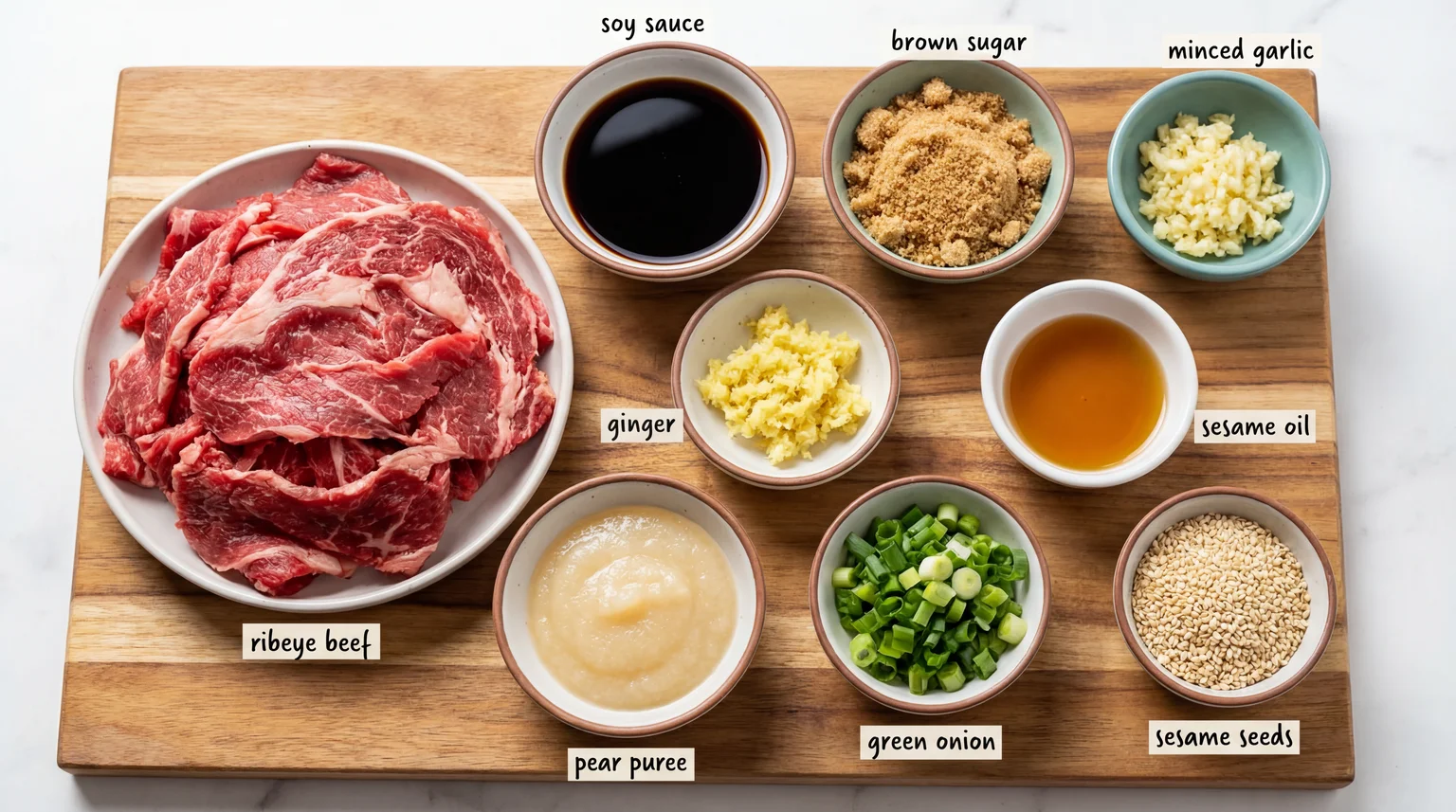 Mise en place ingredients for authentic Korean Beef Bulgogi on wooden board: thinly sliced ribeye, Asian pear puree, soy sauce, brown sugar, sesame oil, garlic, ginger, green onions, and sesame seeds