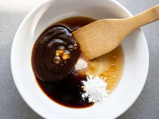 Chinese stir-fry sauce ingredients — oyster sauce, soy sauce, Shaoxing wine, sesame oil, cornstarch, and sugar unmixed in a white ceramic bowl