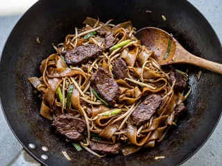 Beef Chow Fun in a carbon steel wok — wide rice noodles with wok-char, seared beef, bean sprouts, and dark soy glaze