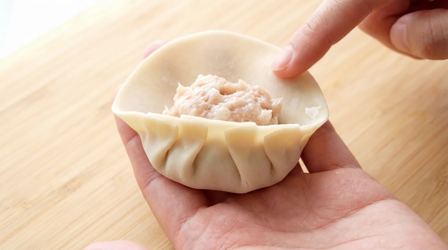 Pleating gyoza wrapper with pork filling, hand folding dumpling with 5-6 pleats on one side
