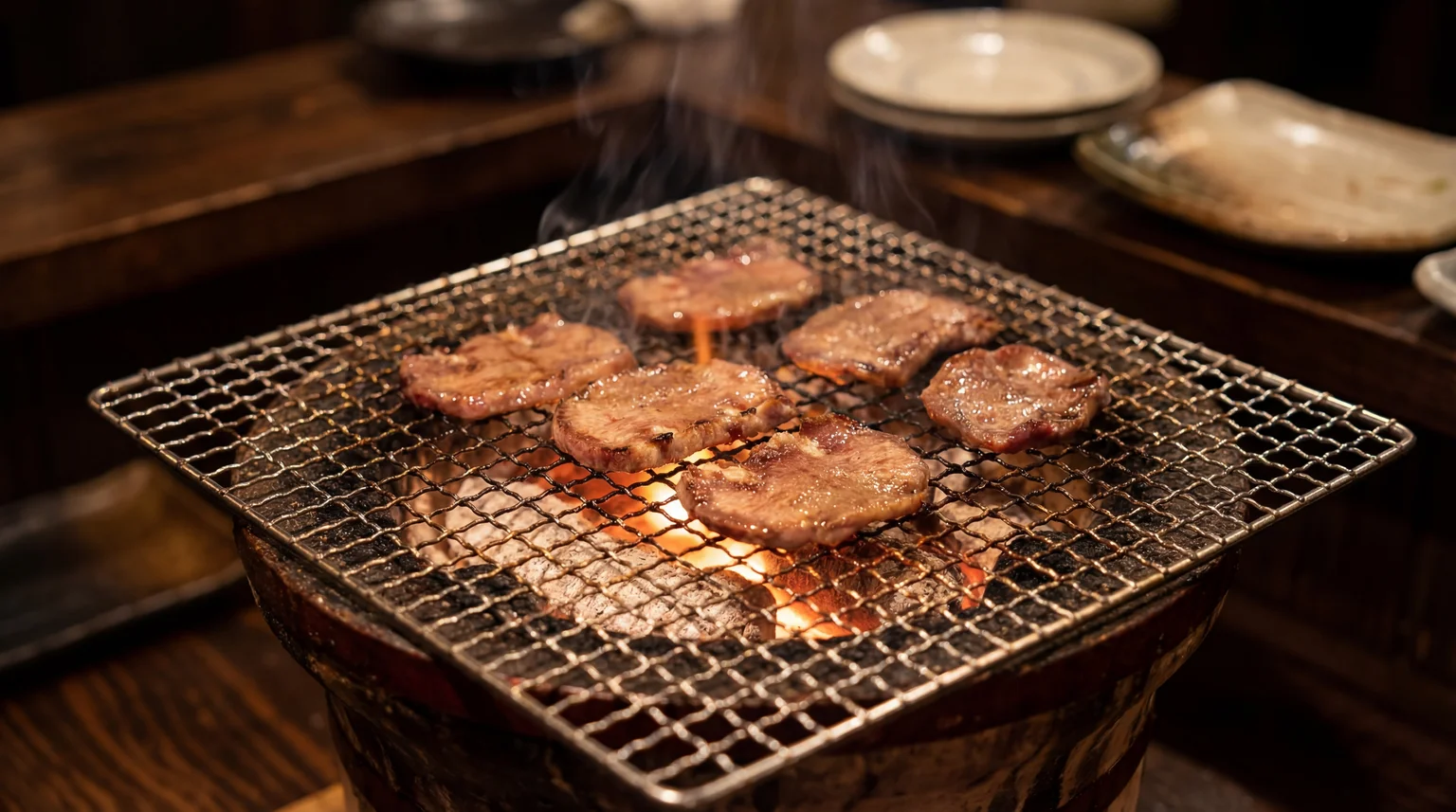 Japanese yakiniku thinly sliced beef grilling over charcoal on wire mesh grill at traditional restaurant
