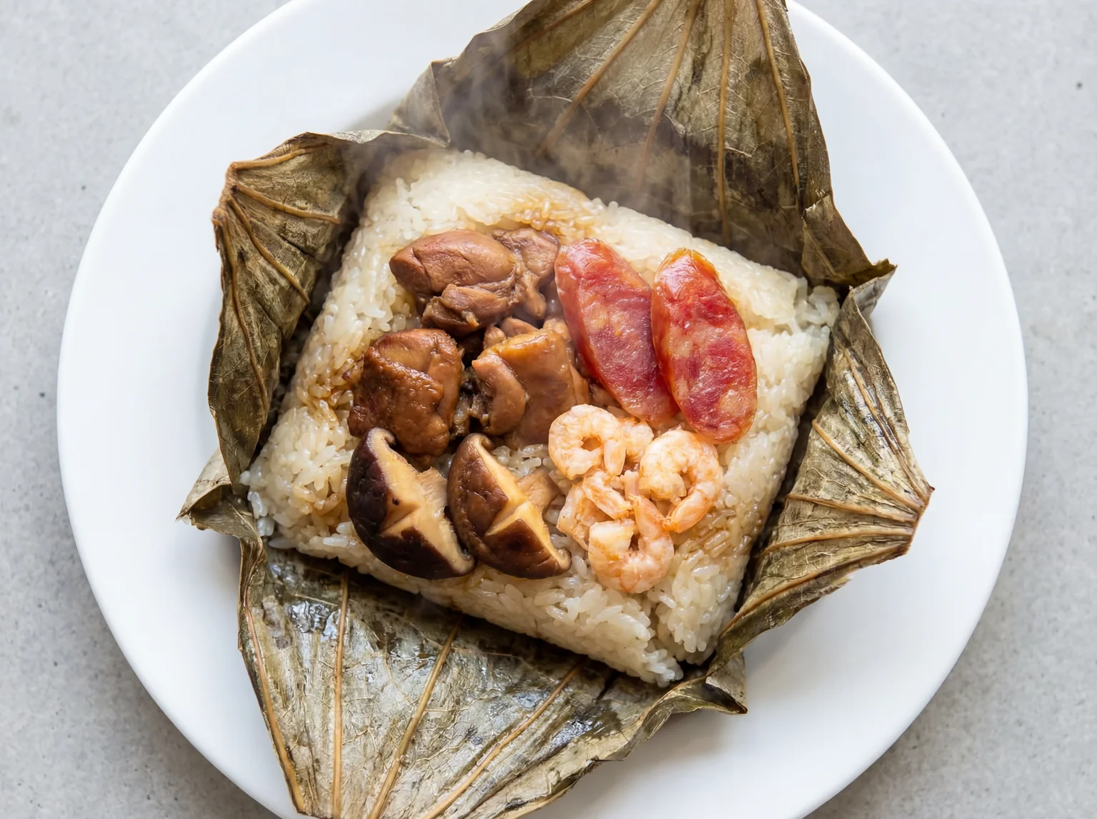 Unwrapped lo mai gai sticky rice parcel in lotus leaf revealing chicken, Chinese sausage, mushroom and dried shrimp filling